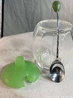 Sugar bowl components: clear pressed crystal glass bowl, green jadeite glass lid with notch for spoon, and spoon with twisted handle and jadeite knob.