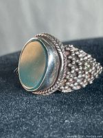 Front view showing oval green stone with surrounding twisted rope bezel and textured band surface.