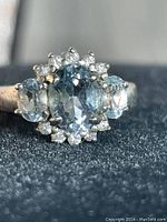 Close-up front view of the vintage sterling silver ring showing central and side blue stones surrounded by clear stones on a silver band.