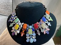 Front view of the necklace showing the full design featuring multi-coloured stones and clear rhinestones set on silver-tone metal.