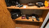 Overview of wooden shelving with multiple film cameras, lenses, cases and video equipment