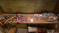 Wide view of pennants laid out and plastic wrapped coin rolling tubes on a wooden shelf