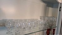 Shelf displaying clear crystal goblets with detailed cut glass patterns in a row.