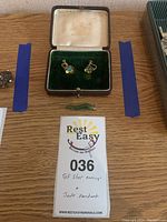 Lot with gold-filled sterling earrings in green velvet box and small jade pendant on wood surface