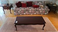 Front view of coffee table in room showing floral sofa and vintage side tables.