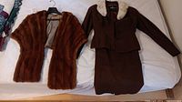 Hudson's Bay red-brown fur stole and brown D'Allards skirt suit with fur collar (jacket and skirt) laid flat on a white surface