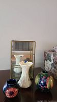 Set of Moorcroft and Belleek vases with brass edged glass display case on table