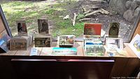 Photo showing 30+ postcards arranged on window ledge, various themes including illustrated and scenic images