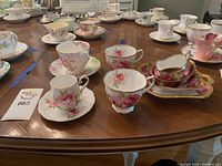 Multiple Royal Albert fine bone china tea cup and saucer sets arranged on table showing various floral patterns and gold trim.