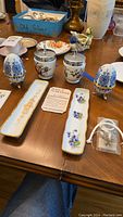 Overview of Royal Worcester egg coddlers, Birks porcelain dishes, and other porcelain collectible items on a table.