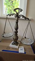 Full view of the vintage brass balance scale with glass weighing plates on chains and marble base.