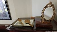 Vanity set consisting of mirrored tray with brush and hand mirror, standing mirror, and decorative box on table