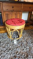 Front view of round bamboo stool with removable red cushion.