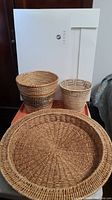 Photo showing three woven baskets on a table with part of a box in background