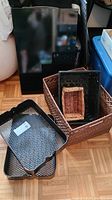 Photo of stacked wicker baskets and two black metal trays on the floor showing different sizes and textures.