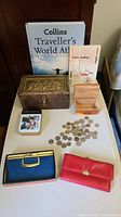 Coins, boxes, books, and wallets displayed on a table, showing the entire assortment of items in the lot.