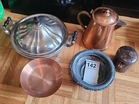 Copper and silver plated service ware including a covered silver plated dish with black handles, copper pitcher, copper bowl, silver plated tray, and pepper shaker.