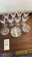 Eight crystal glasses arranged with three crystal dishes on a wooden surface.