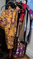 Hangers with assorted clothing items including floral patterned pants, visible behind other garments.
