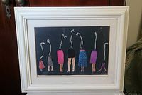 Framed mixed media artwork showing abstract human figures with legs in clothing and strings as upper bodies.