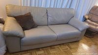 Front view of beige leather sofa with brown throw pillow