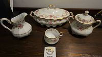 Full set of Limoges china including lidded vegetable dish, creamer, sugar pot, and cup, showing pattern and gold detail