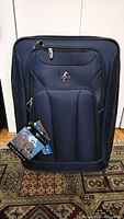 Front view of brand new navy blue Atlantic luggage with tags attached showing multiple zippered compartments.