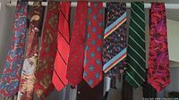 Photo displaying nine neckties hung side by side showing a variety of patterns and colors including floral, geometric, stripes, and abstract designs.