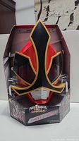 Front view of the red Power Rangers Samurai Shogun helmet in black and gold design inside original open box packaging.