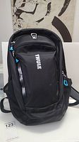 Front view of the black Thule laptop backpack with logo and zipper pulls.