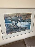 Framed art print showing a landscape scene with trees, rocks, and flowing water signed by M. Sloan.