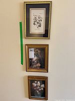 Three framed floral artworks mounted vertically on wall, showing relative size and framing styles