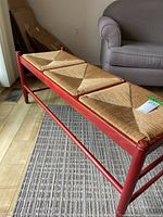 Side angle showing the reddish wooden frame and natural wicker triangular seat sections.