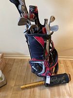 Full view of Wilson golf bag packed with clubs and visible golf ball retriever leaning against base