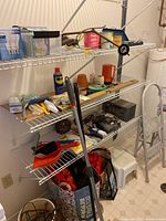 Metal shelving with assorted tools, lightbulbs, cleaning items and step stools visible