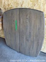 Photo of the grey pressboard dining table top detached, showing wood grain finish and rectangular shape with rounded corners.