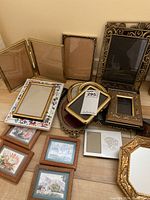 Various picture frames in multiple styles and sizes with ornate and wood finishes, small picture prints included