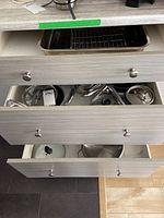 Wide view of open kitchen drawers holding various pots, pans, and lids