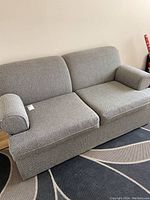 Front angle view of grey fabric sofa bed on area rug