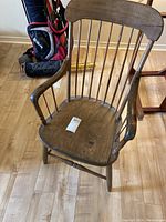 Front view of vintage wooden armchair showing curved backrest, spindle supports, and armrests.