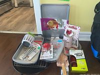 Overview of the baking supplies lot including cookie sheet, cutters, icing pen, fruit fly traps, melon baller, oven mitt, cooling rack and some utensils