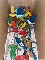 Box containing 14 colorful, hand-painted decorative metal birds on stakes with flapping wings, in various colors including red, yellow, blue, green, and white.