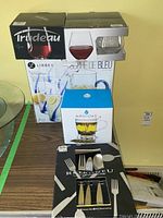 Overall lot showing Trudeau wine glasses, Libbey pitcher with glasses, and Retroneu flatware set boxed