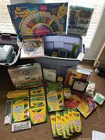 Wide view of all art supplies including paint by numbers kit, assorted Crayola markers and colored pencils, storage bin, and notebooks.