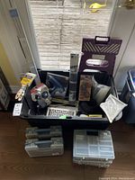 Lot contents overview with tackle boxes, paint brushes, glue supplies, cable clamps, step stool, and bin.