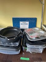 View of grouped assorted pans and baking tins including boxed Cuisinart bakeware and Wilton dessert shells pan.