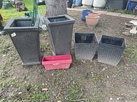Two tall dark brown woven-style planters, two smaller square woven-style planters and four small plastic planter boxes arranged on the ground outdoors.