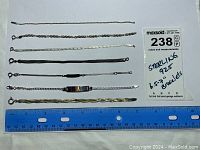 All 7 sterling silver bracelets laid parallel on a white surface with ruler for size and label stating 6.5"-7" length