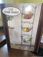 Box front showing image of the three tier scroll basket with fruits inside.