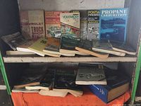 Two shelves filled with automotive repair manuals including Chevrolet, Dodge, Volkswagen, Pontiac, and Propane carburetion book among others.